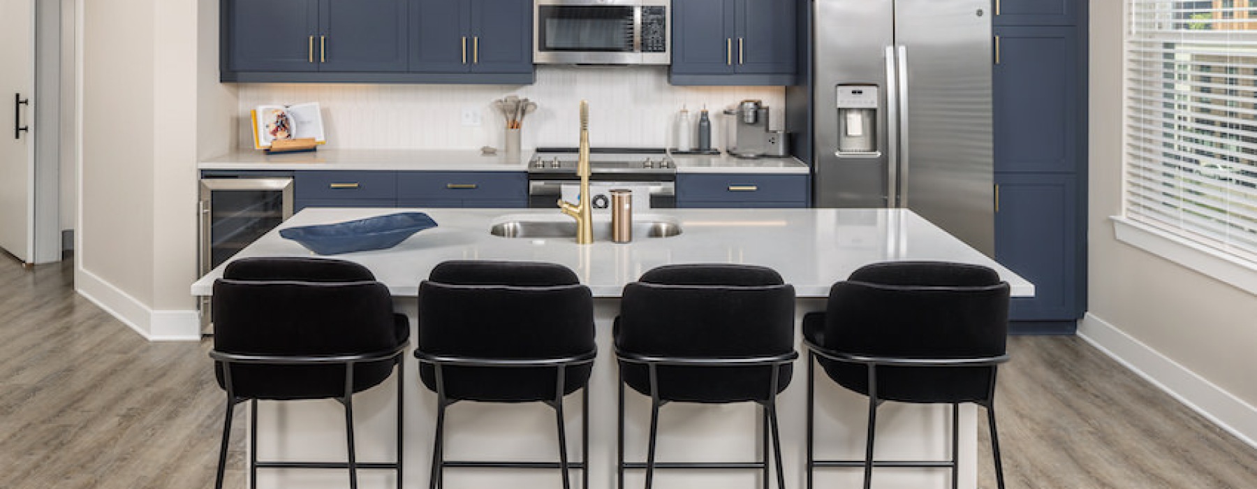 Blue kitchen cabinets with island and bar stools
