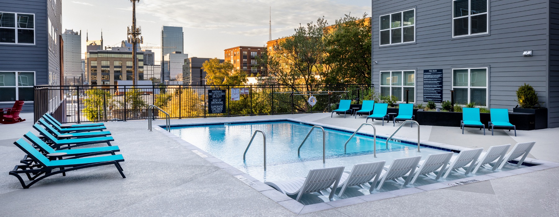 Pool lounge at our apartments for rent in Nashville, TN, featuring beach chairs and a view of the apartments.