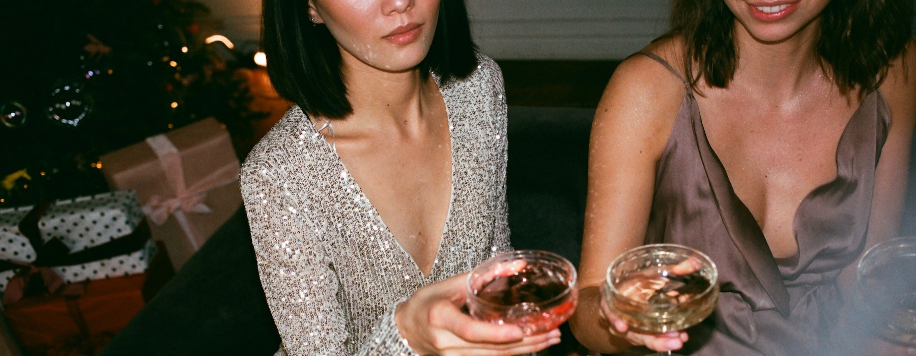 lifestyle image of glossy dresses and women holding their cocktails