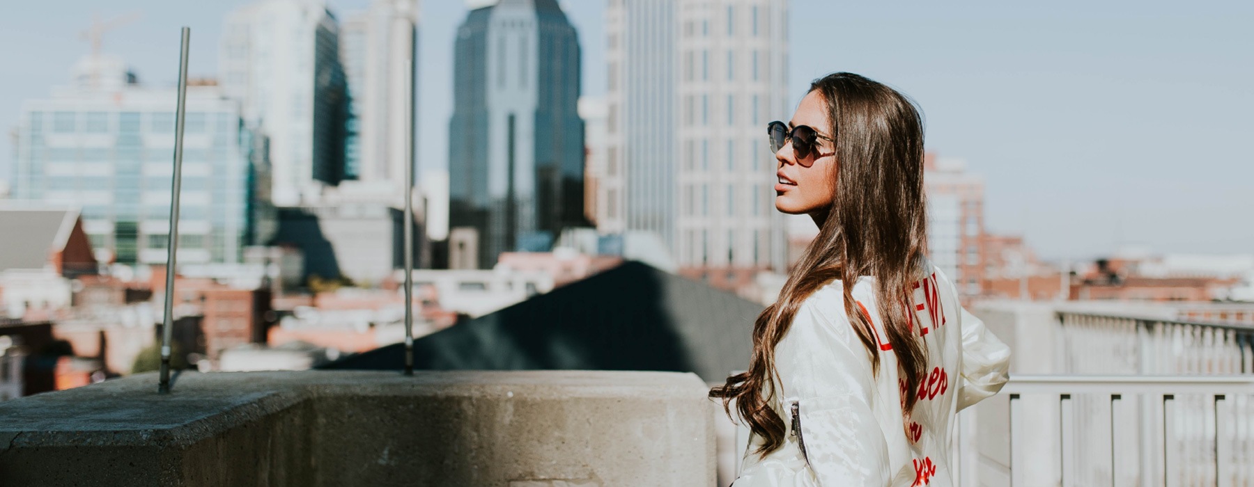 lifestyle image of a business woman looking off into the distance with a towering city skyline in the far-off background