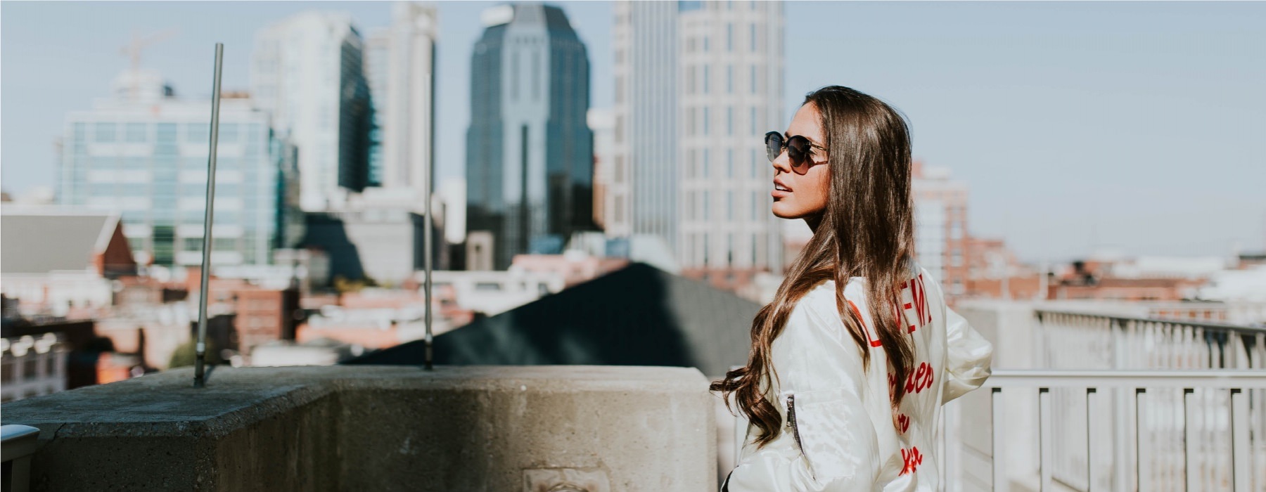 lifestyle image of a business woman looking off into the distance with a towering city skyline in the far-off background